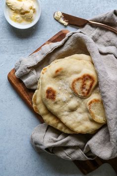 two pita breads on a cutting board next to a bowl of yogurt