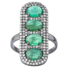 an emerald and diamond ring with three oval stones on each side, set in white gold