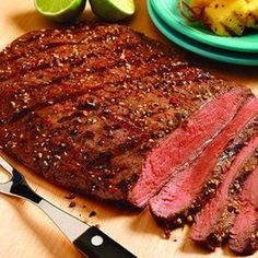 steak, potatoes and limes on a cutting board next to a plate of food