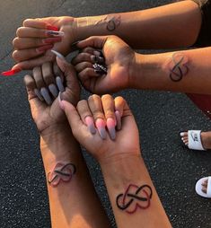 group of people holding hands with tattoos on their arms and fingers together in a circle