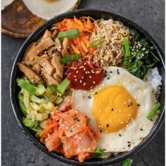 a black bowl filled with rice, meat and veggies next to an egg