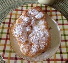 a plate topped with powdered sugar on top of a checkered table cloth next to an egg