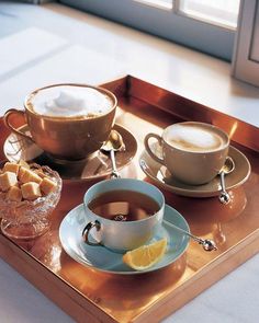 two cups of coffee on a tray with lemon wedges and marshmallows