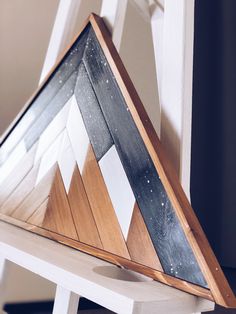 a triangle shaped piece of wood sitting on top of a white chair next to a wall