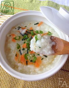 a bowl filled with rice and carrots on top of a table next to a spoon