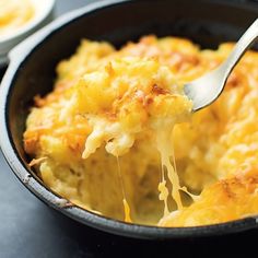 a close up of a spoon in a casserole dish with cheese on it