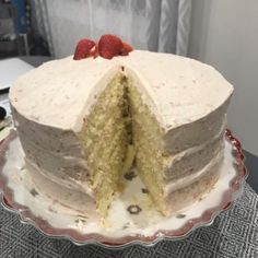 a cake with white frosting and raspberries cut in half on a plate