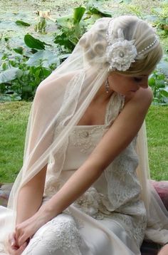 a woman in a wedding dress sitting on the ground with her veil over her head