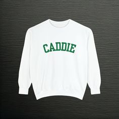 a white sweatshirt with the word caddie in green on it, against a black background