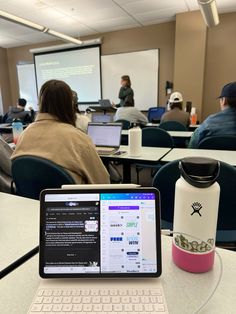 a laptop computer sitting on top of a table in front of a class room full of people