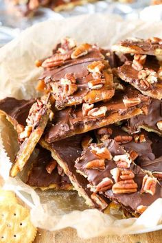 a pile of chocolate pecan bars on top of a wooden table next to crackers