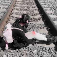 a woman sitting on the train tracks with her legs crossed and head in her hands