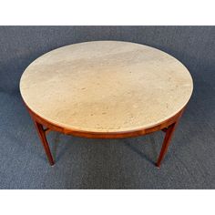 a round marble top coffee table with wooden legs on carpeted flooring in an empty room