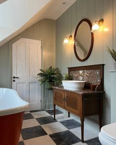 a bathroom with a checkered floor and white tub in the corner next to a round mirror