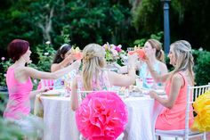 four women sitting at a table with plates and cups in front of them, one holding a watermelon