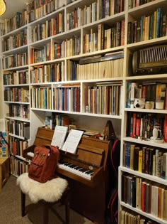 a room filled with lots of books and a piano in front of a book shelf