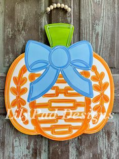 an orange and blue sign with a bow on it's head hanging from a wooden door