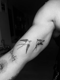 a man with a tattoo on his arm that has two birds flying in the sky