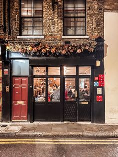 the entrance to a restaurant with people sitting at tables on the outside and in the front