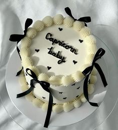 a white cake with black ribbon and congratulations written on the top is sitting on a glass plate