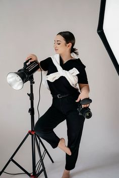 a woman is posing with a camera and light