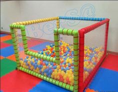 an indoor play area with balls in the net and colorful tiles on the floor around it