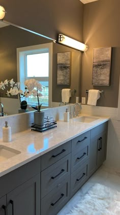 a large bathroom with two sinks and a big mirror above the sink is decorated with white flowers