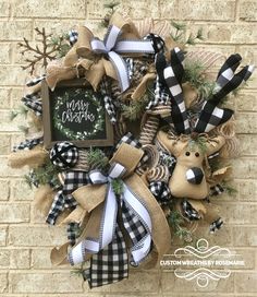 a christmas wreath hanging on the side of a brick wall with black and white bows