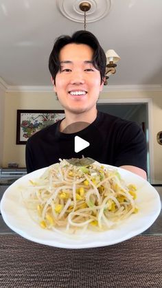 a man holding a plate of food in front of his face and smiling at the camera