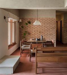 a dining room with brick walls and wooden furniture in the center, along with potted plants