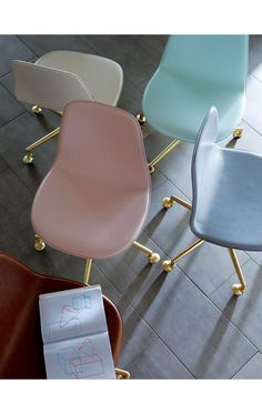 four different colored chairs sitting next to each other on top of a tile floor with gold legs