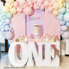 there is a table with balloons and cake on it in front of a sign that says one