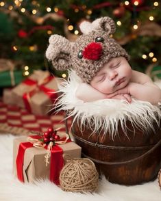 a baby sleeping in a bucket next to presents