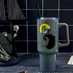 a halloween themed coffee cup sitting on top of a counter next to a skeleton figurine