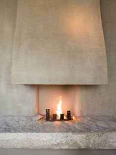 a fireplace with some candles in front of it and a light on the wall behind it