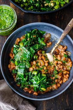 two bowls filled with beans and greens on top of a wooden table