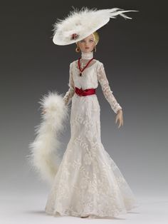 the doll is wearing a white dress and hat with feathers on it's head