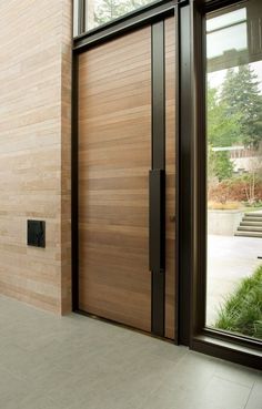 a large wooden door sitting inside of a building next to a tall window on the side of a wall