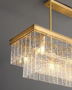 a chandelier hanging from the ceiling in a room with grey walls and gold fixtures