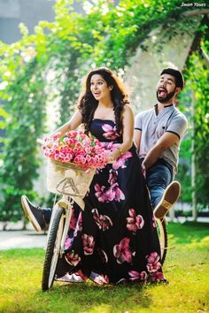 a man riding a bike next to a woman in a floral dress and holding flowers