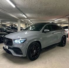 a mercedes benz suv is parked in a parking garage with other cars lined up behind it