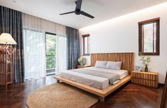 a bedroom with wood flooring and white walls, along with a large bed on top of a wooden platform