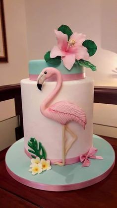 a pink flamingo cake sitting on top of a wooden table next to a flower