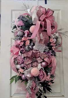 a wreath is hanging on the door with pink ribbons and flowers around it's edges