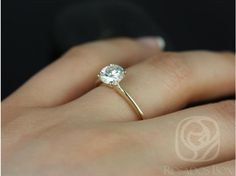 a woman's hand with a diamond ring on top of her finger, showing the center stone