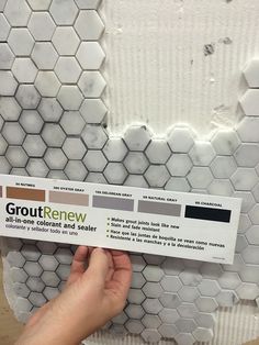 a person is holding up a sticker on a tile wall with hexagonal tiles