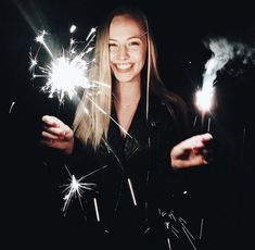 a woman holding two sparklers in her hands