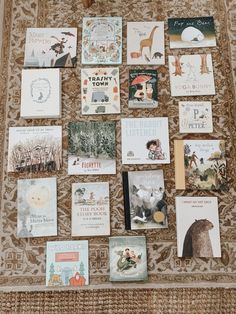 many children's books are arranged on a rug in front of a wall hanging