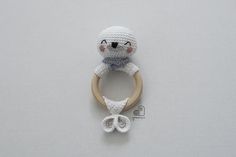 a crocheted stuffed animal with a wooden ring around it's neck on a white surface