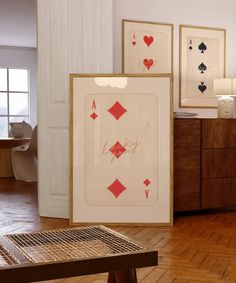 two framed playing cards sitting on top of a hard wood floor next to a table